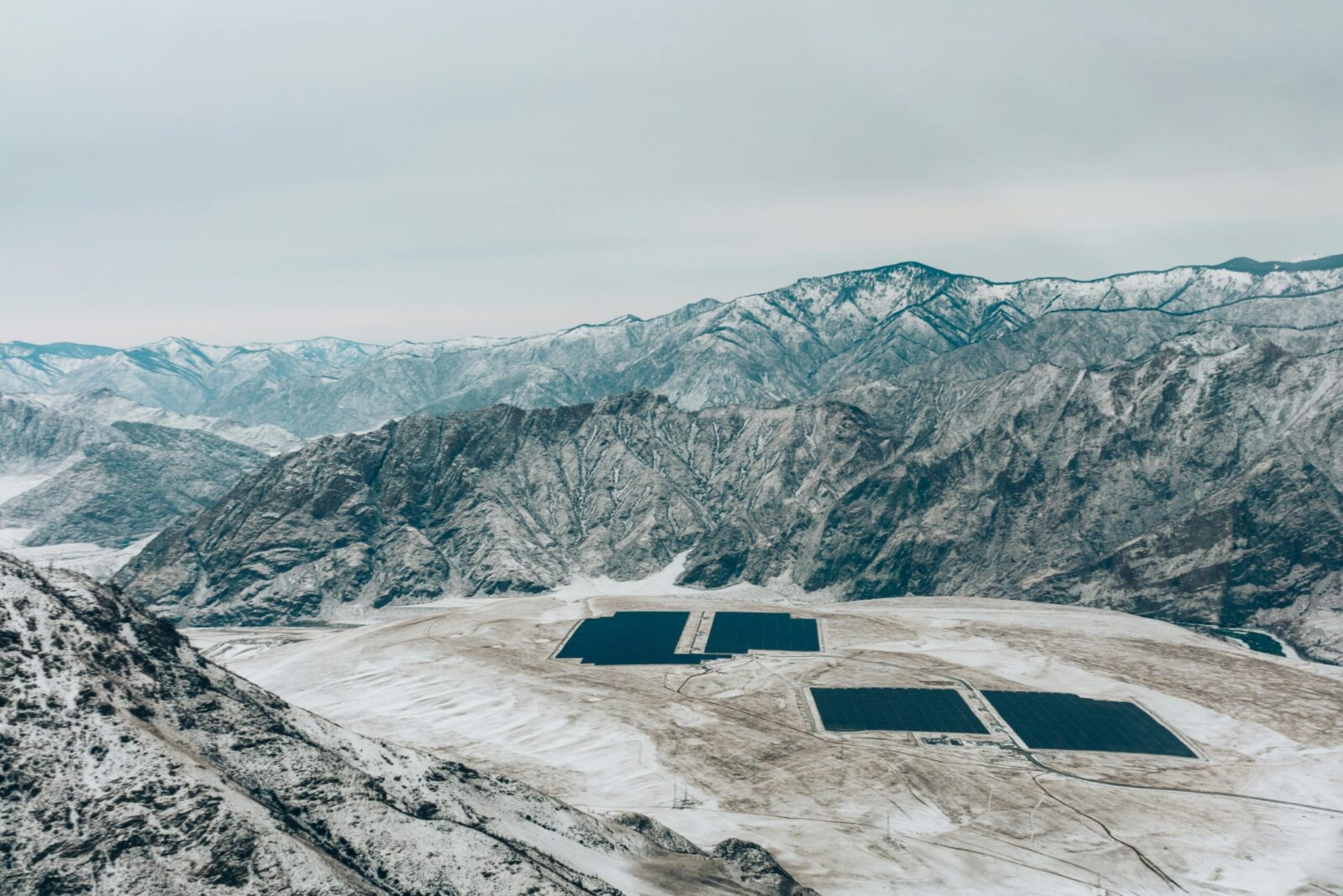 Aerial view of a snow-covered mountain landscape with solar panels.